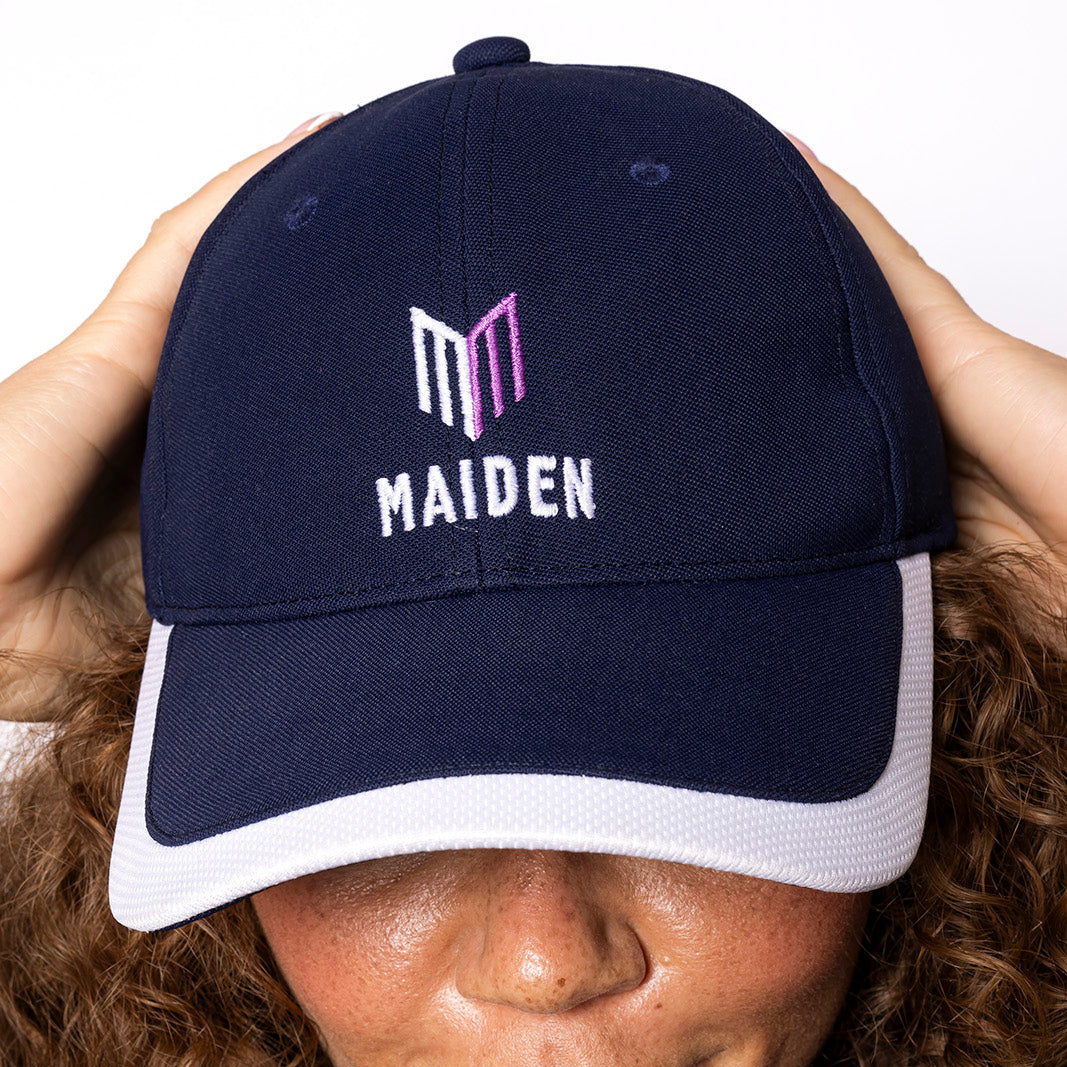 Person wearing a navy blue cap with 'MAIDEN' logo on a white background