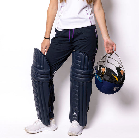 Person wearing cricket gear including a helmet and pads on a white background