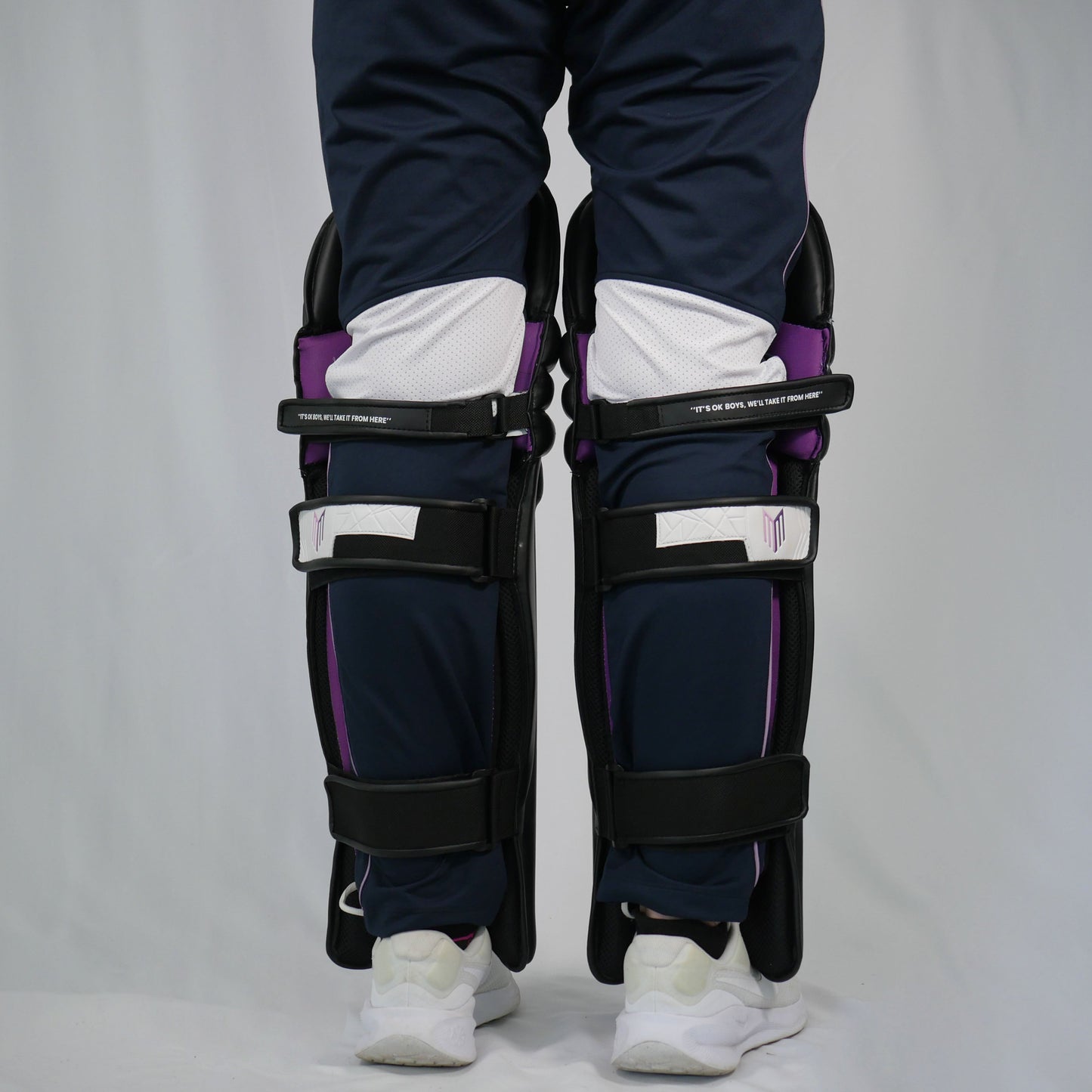 Person wearing black shin guards with purple accents on a plain background