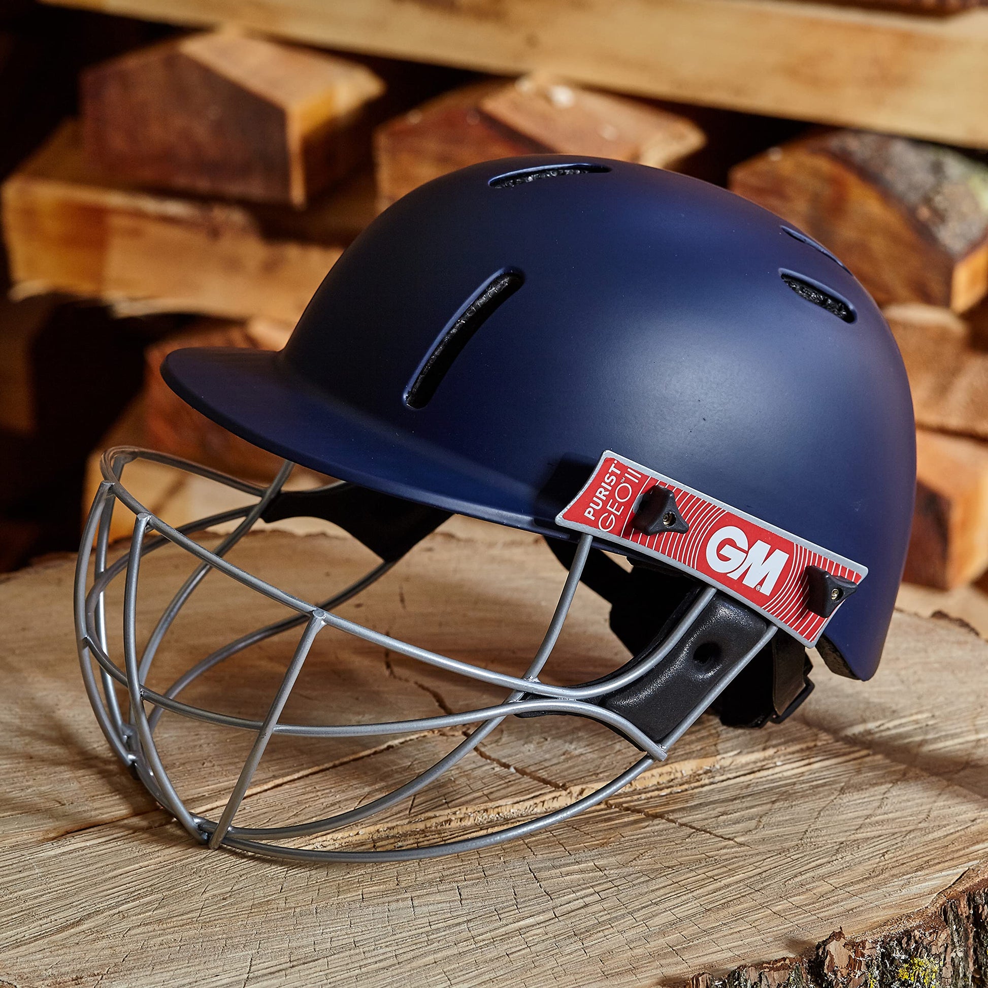 Blue cricket helmet with face guard on a wooden surface