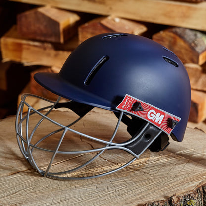 Blue cricket helmet with face guard on a wooden surface