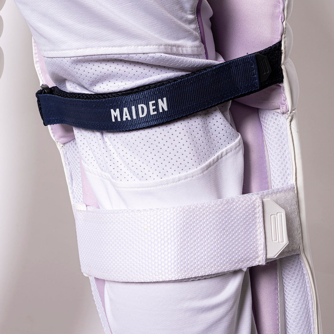 Close-up of a white and purple equestrian leg guard with a black strap labeled 'MAIDEN' on a plain background.
