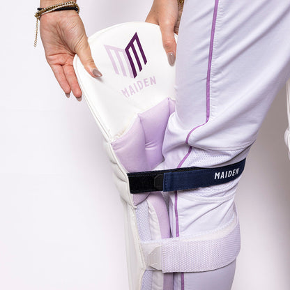 Person wearing a white outfit with purple accents, holding a white box with 'MAIDEN' branding.