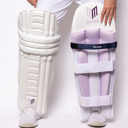 Person wearing white cricket pads with 'Maiden' branding on a light gray background