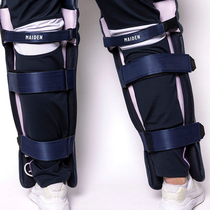 Navy leg guards with white accents on a person wearing black pants and white shoes against a white background.