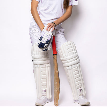 Person wearing a cricket uniform with a bat and gloves on a white background