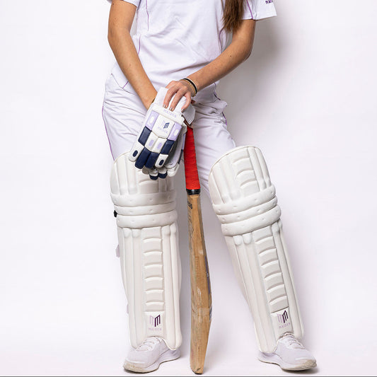 Person wearing a cricket uniform with a bat and gloves on a white background