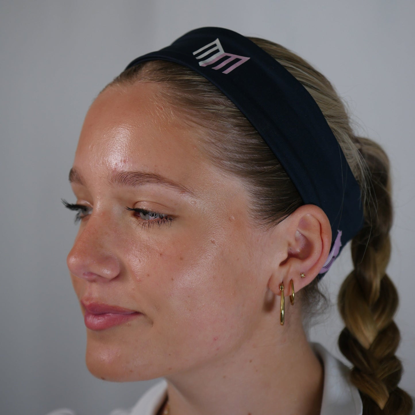 Woman with braided hair wearing a black headband against a plain background
