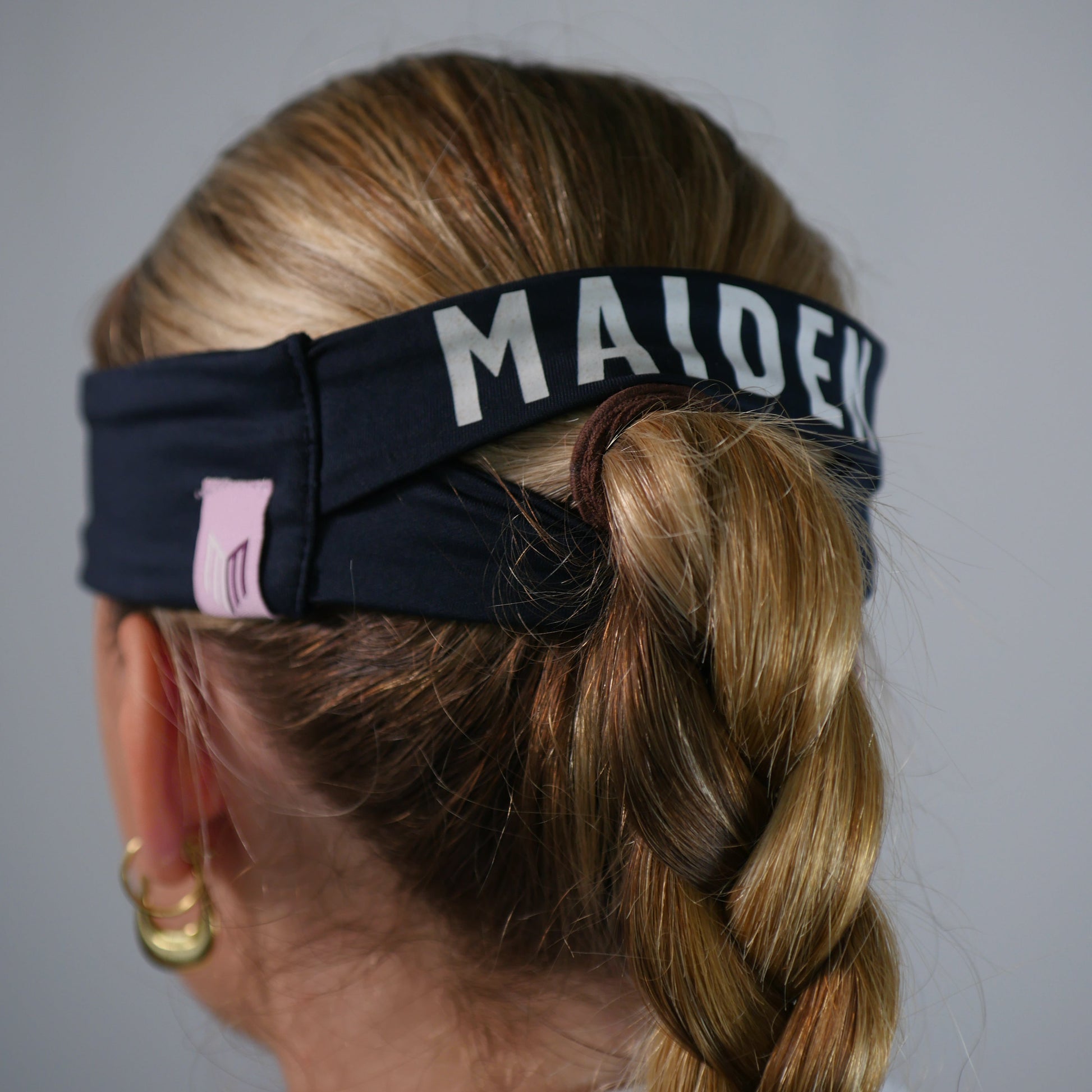 Person with braided hair wearing a headband with 'MALDEK' branding on a plain background