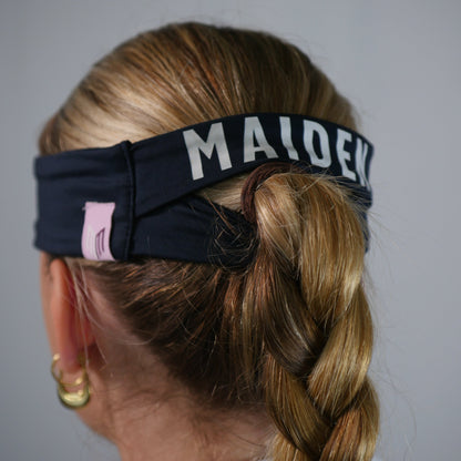 Person with braided hair wearing a headband with 'MALDEK' branding on a plain background