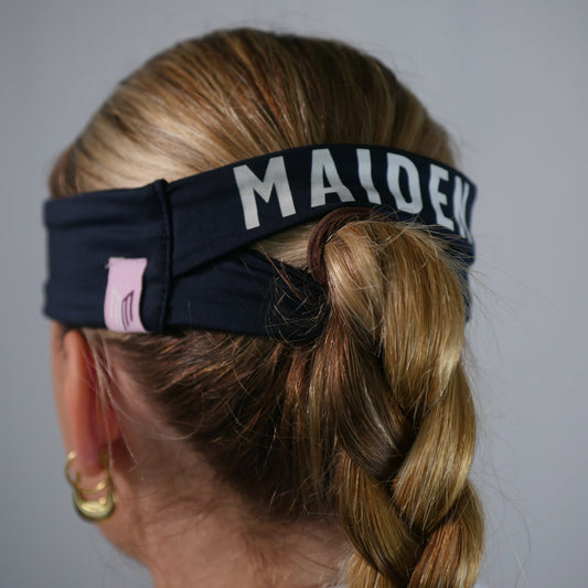 Person with braided hair wearing a headband with 'MALDEK' branding on a plain background