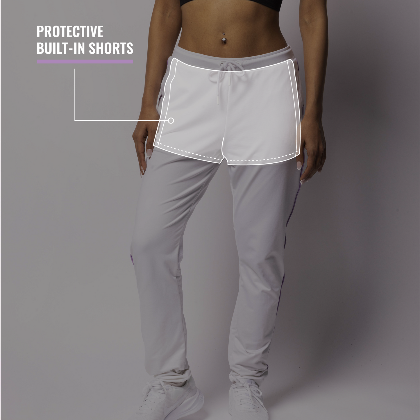 Person wearing a black sports bra and gray pants with built-in shorts on a gray background