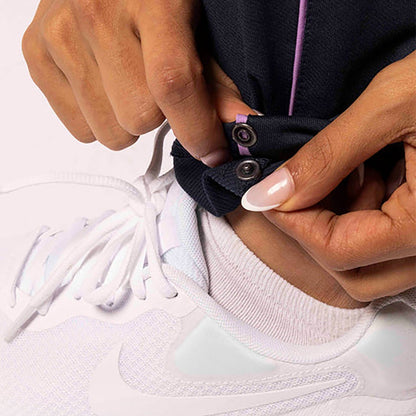 Person adjusting a black shoe lace on a white sneaker against a white background