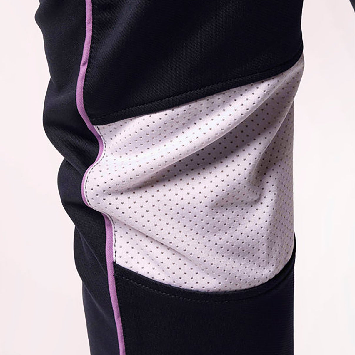 Close-up of a black and white athletic outfit with pink trim on a light pink background