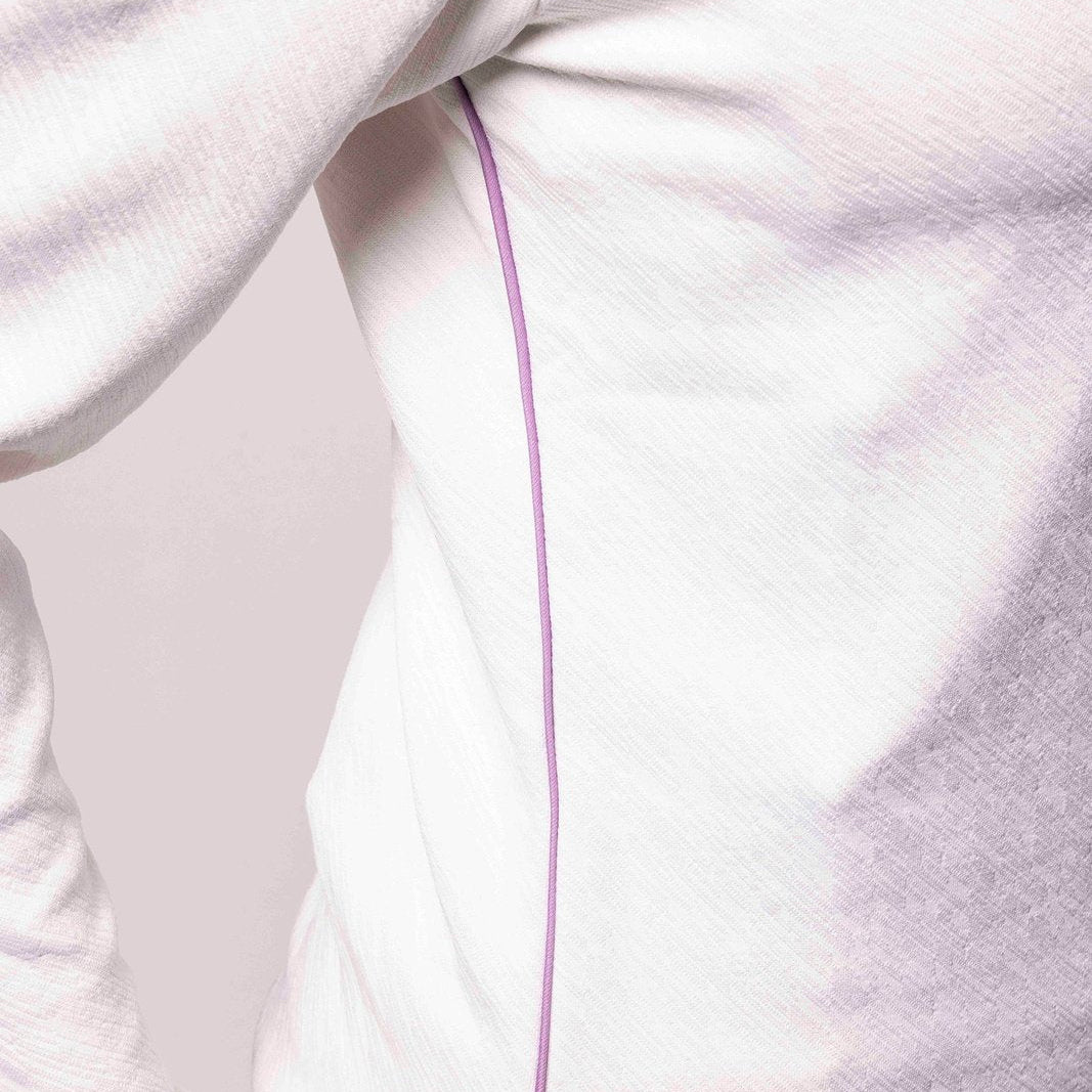 Close-up of a white garment with a purple line on a plain background