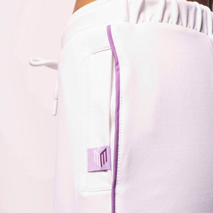 Close-up of a white garment with a purple zipper and button on a light background