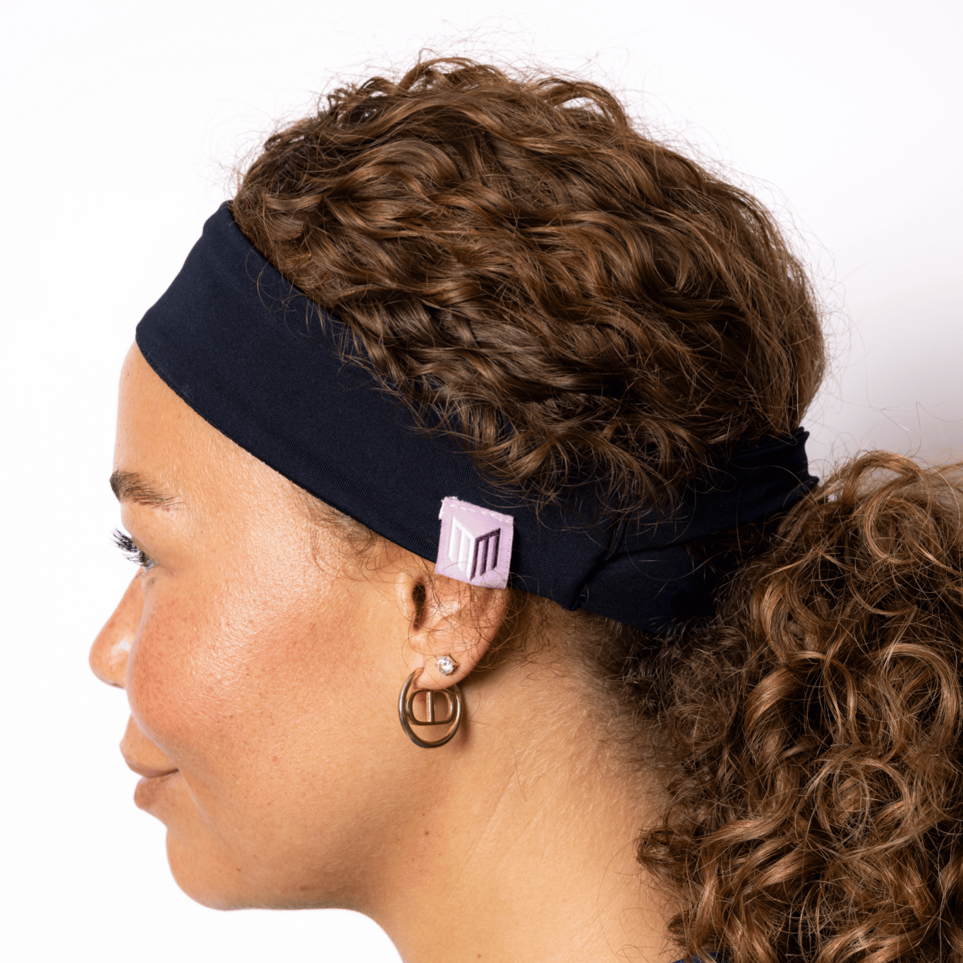 Woman wearing a black headband with a visible brand logo on a white background