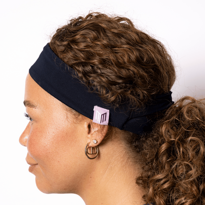 Woman wearing a black headband with a visible brand logo on a white background