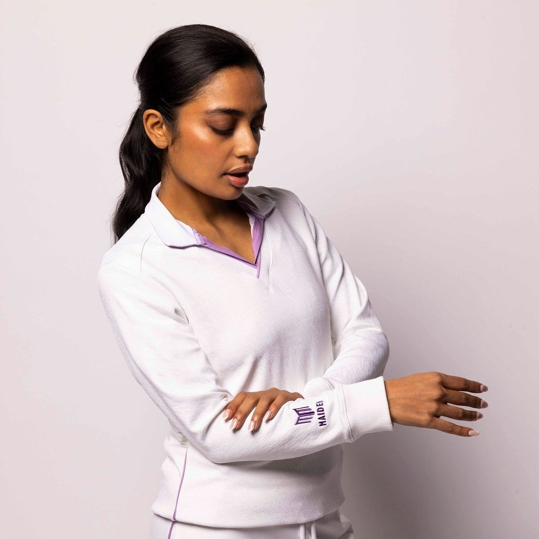 Woman wearing a white tracksuit with a logo on a light gray background