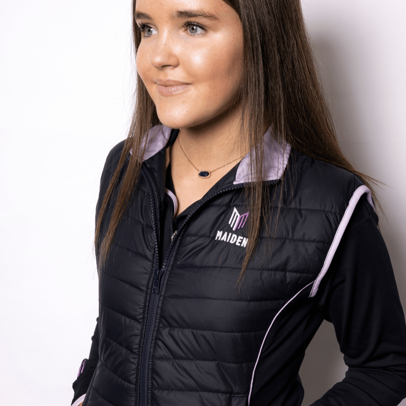 Person wearing a black quilted gilet with a logo on a white background