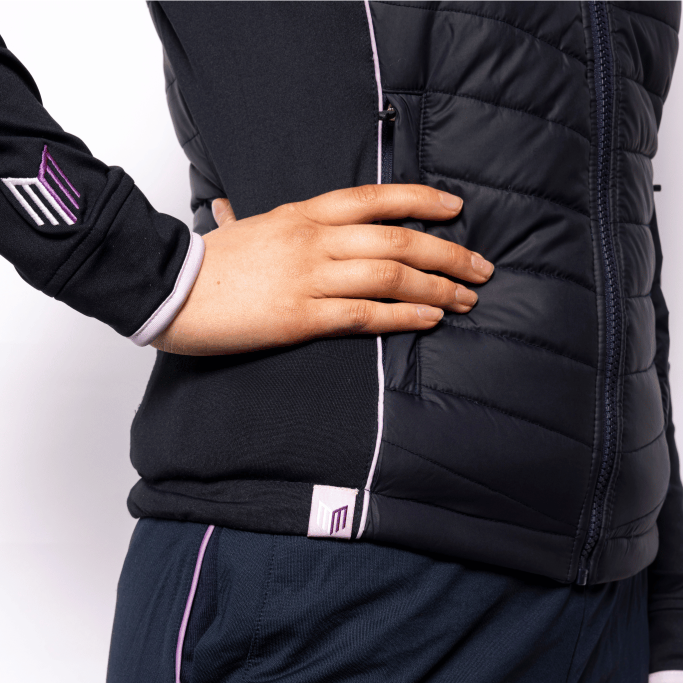Person wearing a black gilet and navy tracksuit with visible branding on a white background